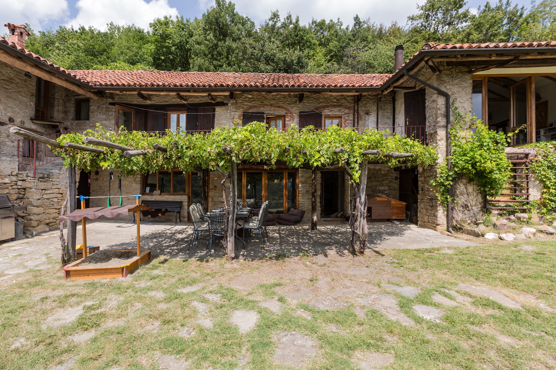 Old stone farmhouse courtyard with grapevine pergola