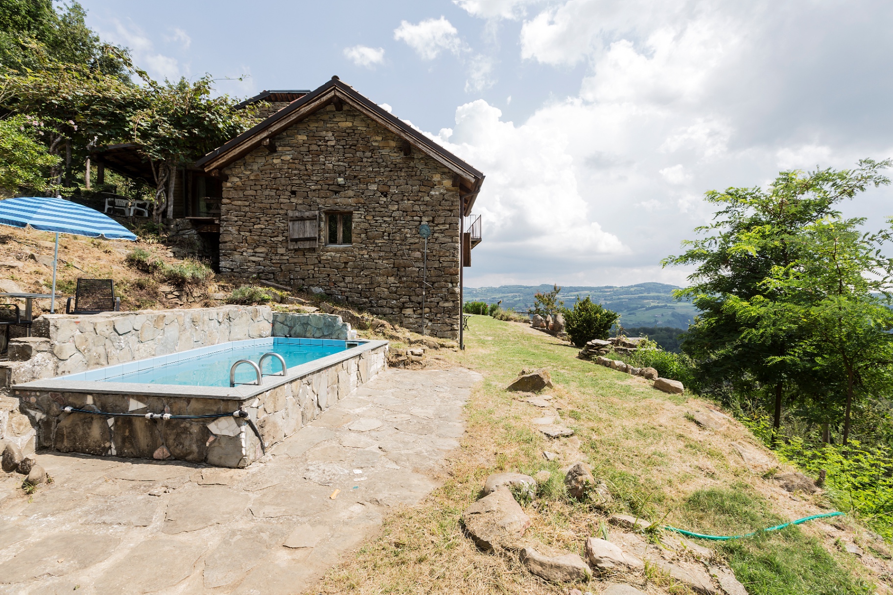 Stone-edged pool beside the farmhouse, with a long view over the Langhe